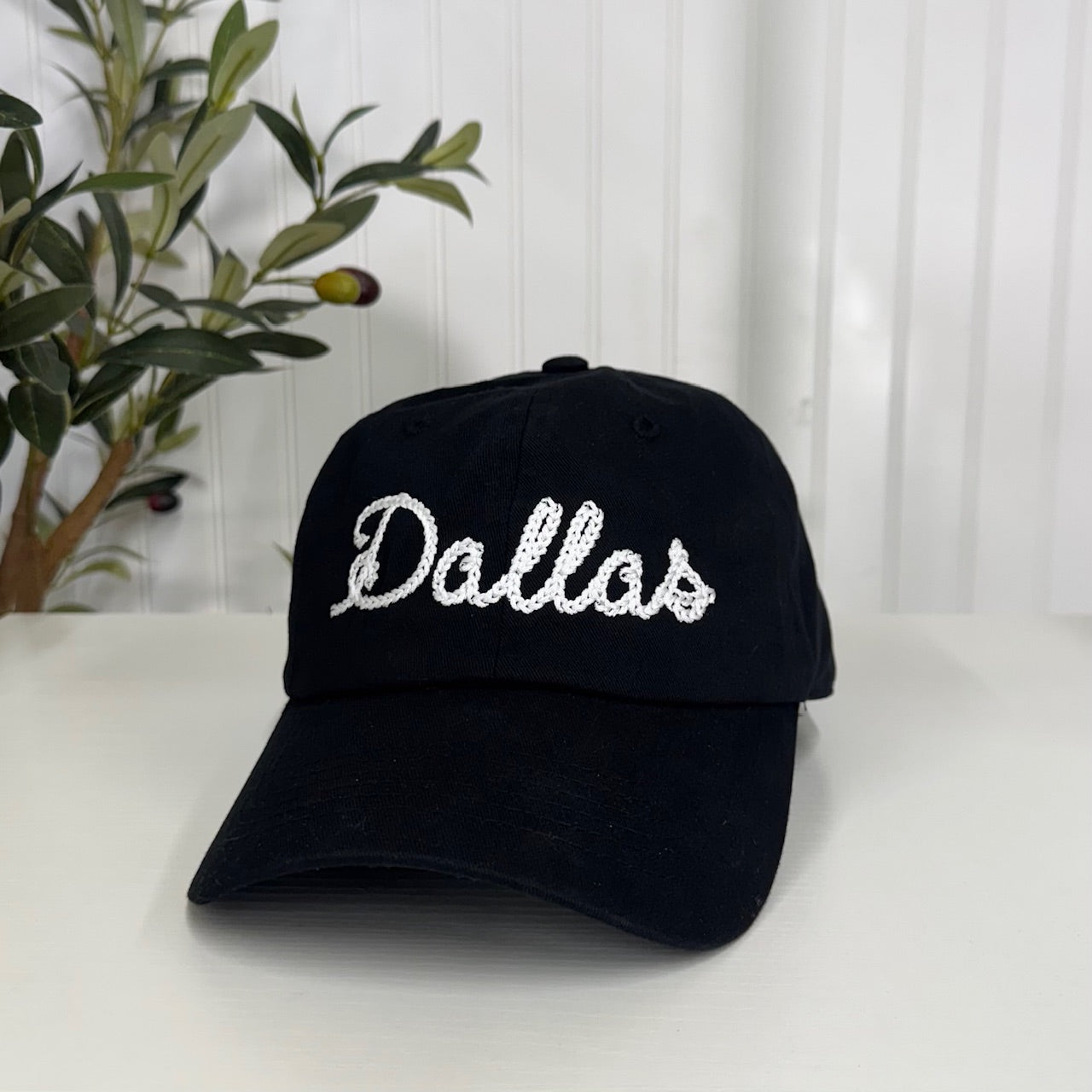 Black baseball hat with &quot;Dallas&quot; embroidered in chain stitch cursive, offering a classic and stylish way to rep your city - DSY Lifestyle