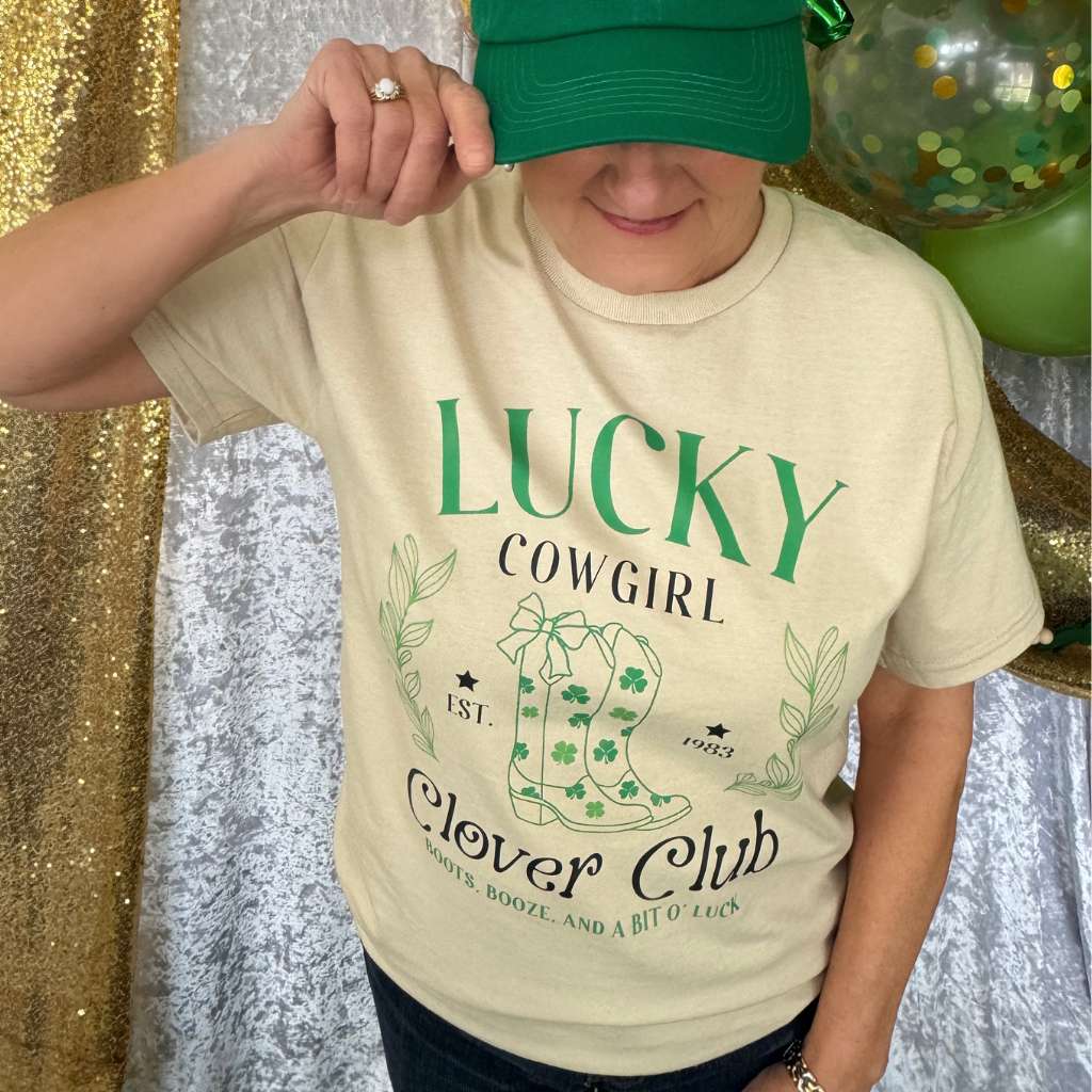 Woman wearing a sand color unisex shirt with Lucky Cowgirl with boots clover club for St Patricks Day - DSY Lifestyle