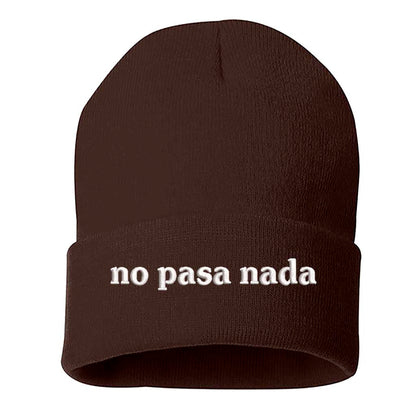 Flat lay of No Pasa Nada Spanglish brown beanie, a cozy winter hat with chill vibes