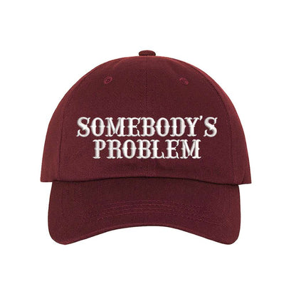 Burgundy baseball hat embroidered with the phrase somebody&