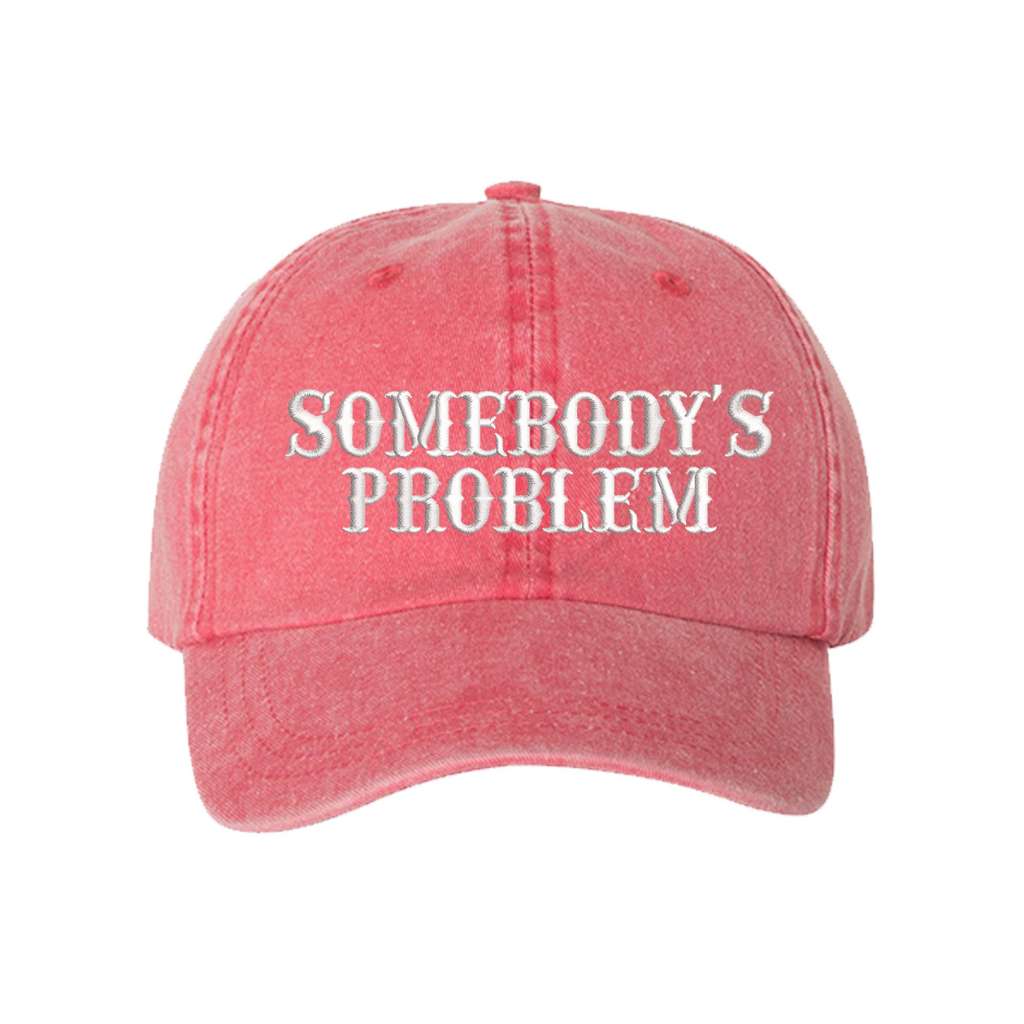Washed coral baseball hat embroidered with the phrase somebody&