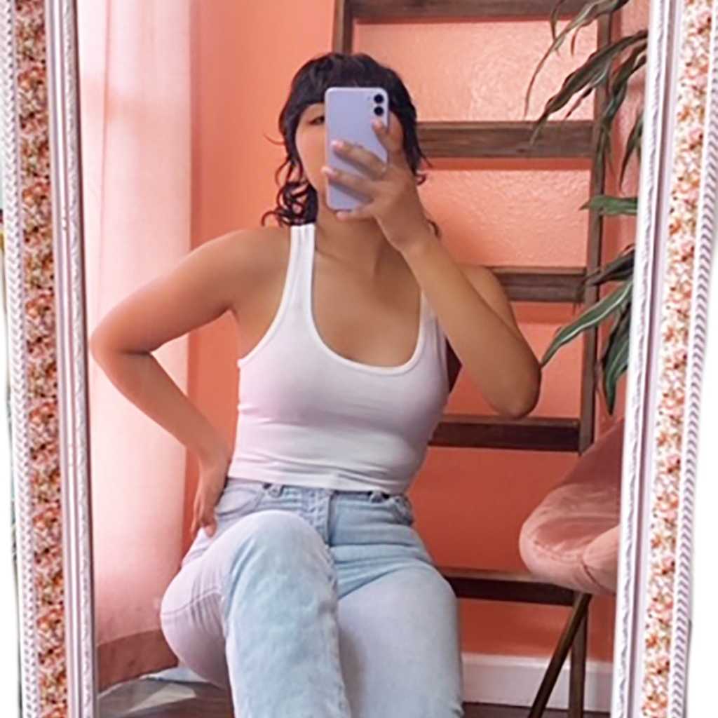 female in front of a mirror tanking a selfie with a white Racerback crop tank top and denim jeans-DSY Lifestyle