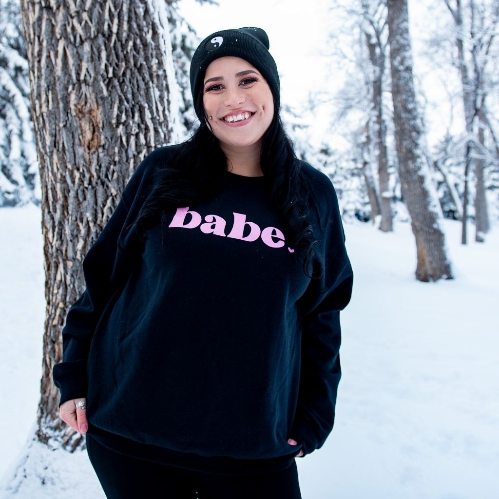 Female in the snow wearing a black sweatshirt with babe printed in pink - DSY Lifestyle